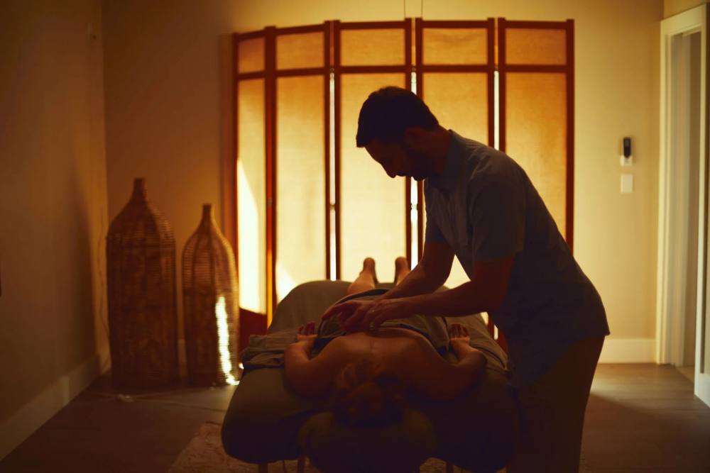 Therapist giving a massage in a softly lit treatment room at ChoZen