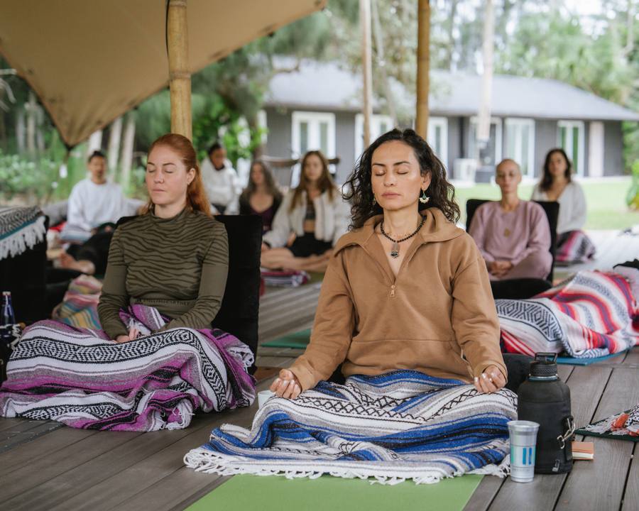 Woman meditating on a blanket during a group retreat session at Wilderness Camp, ChoZen