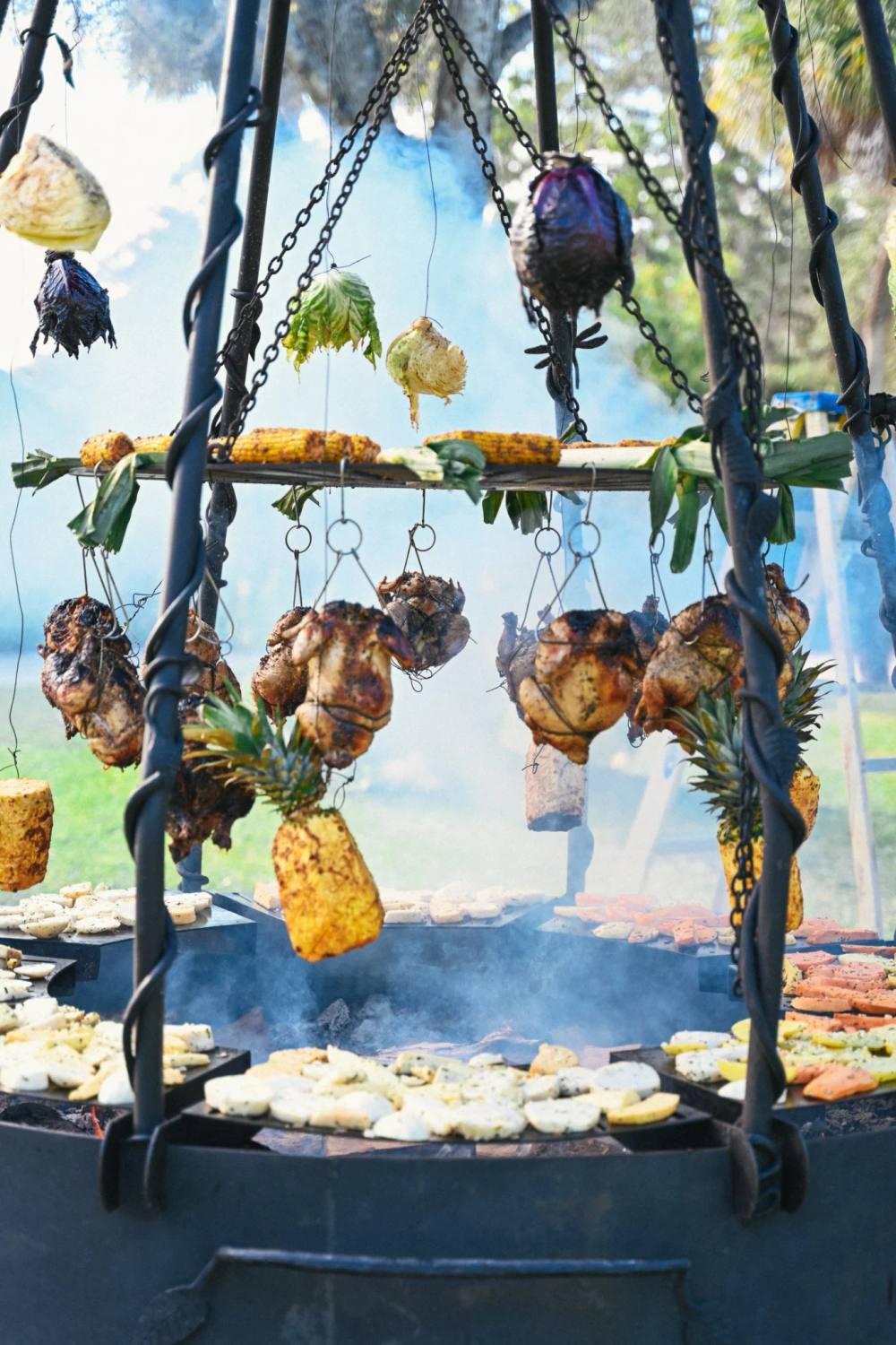 Whole chickens, pineapple and vegetables hanging over an open-fire Argentinian grill at ChoZen