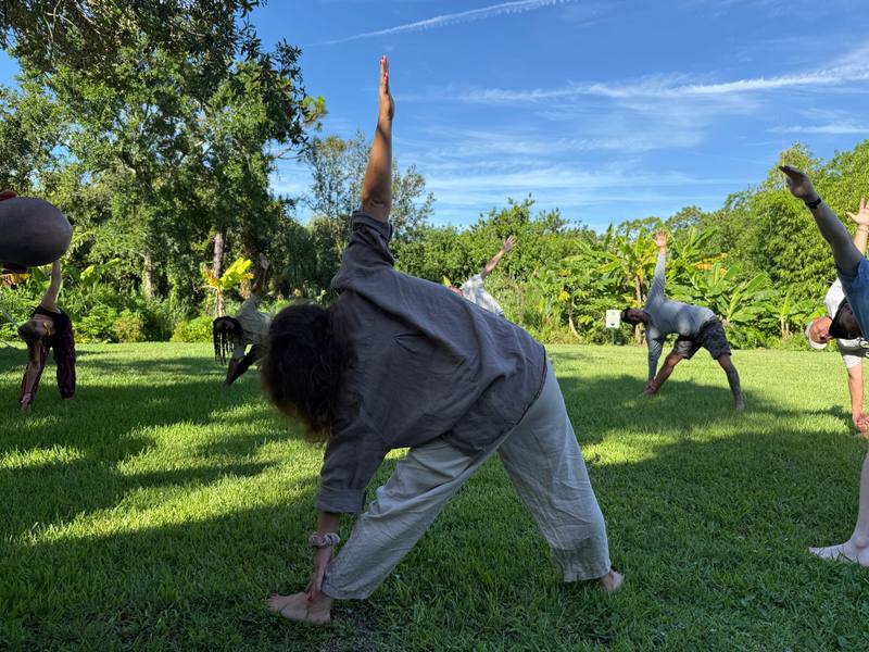 Guests stretching into triangle pose on the lawn during an outdoor yoga session at ChoZen