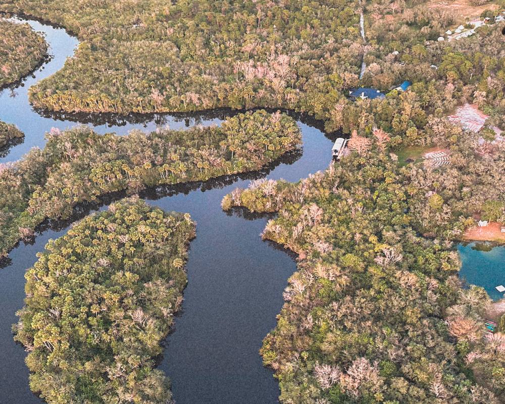 Aerial view of a winding river through palm and oak forest near ChoZen in Sebastian, Florida