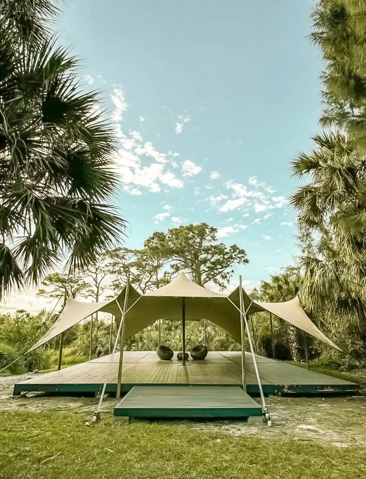 The Wilderness Camp event tent with a wooden deck stage among pines and palms at ChoZen