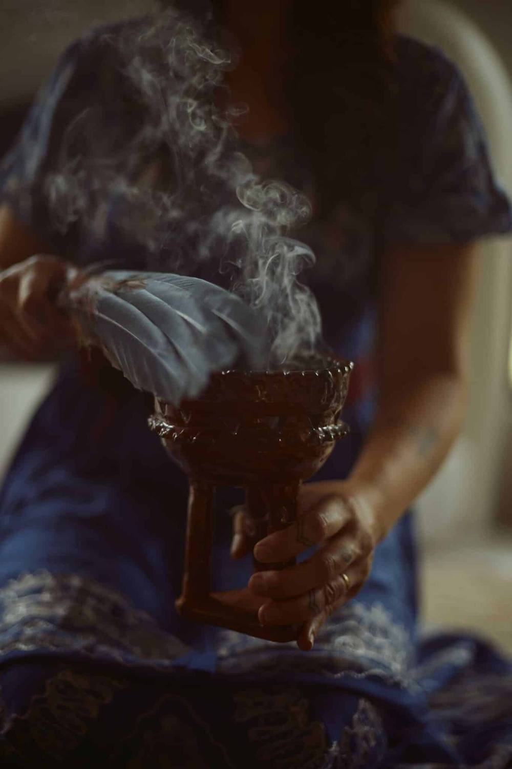 Smudging ceremony with feather and smoking incense bowl